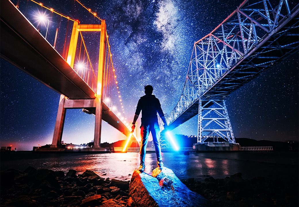 Man with lightsabers under a bridge